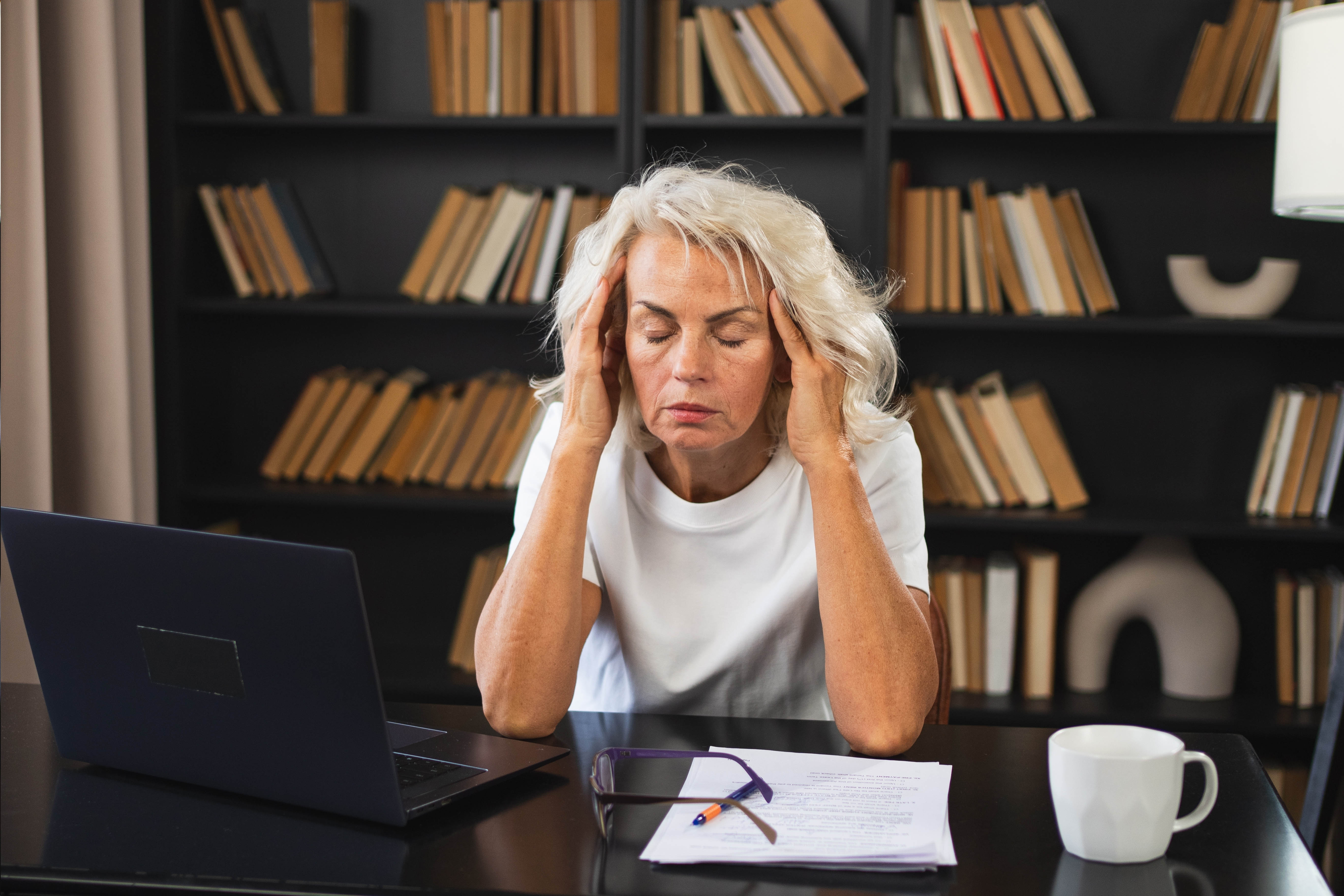 Stressed middle aged woman with her hands on her temples